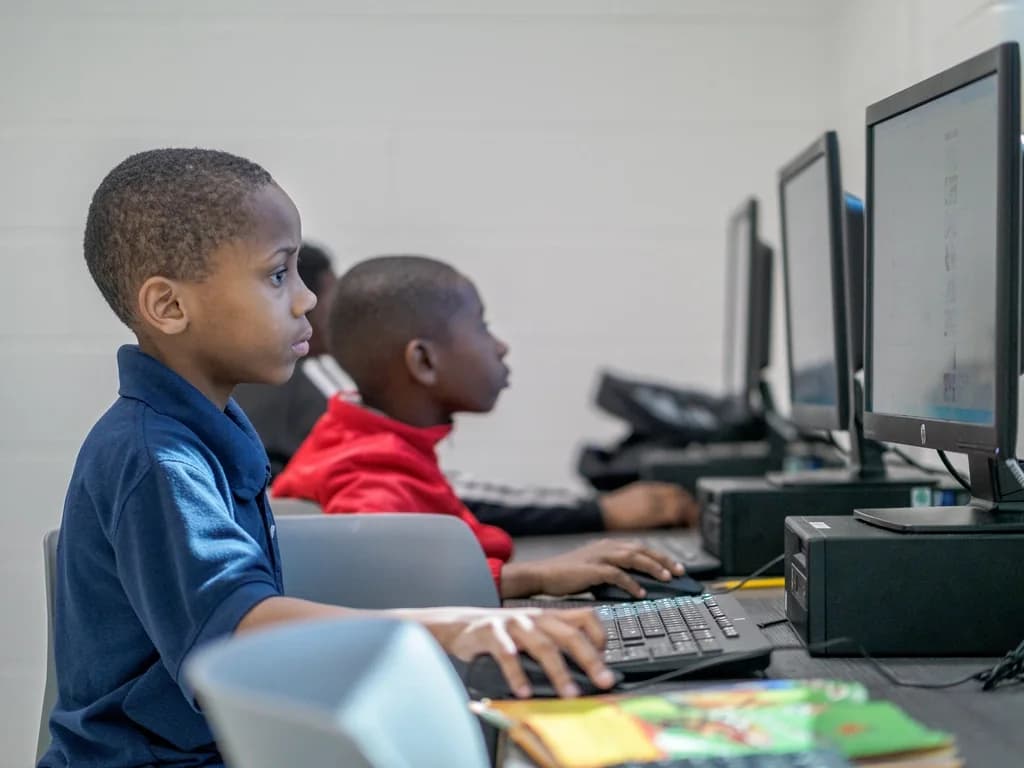 Two children working at desktop computers in an after-school computer room